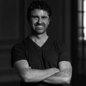 Black and white photo of a man with arms folded.