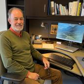 Doctor seated at a desk in front of computer monitor. 