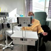 A woman sits in a recliner chair in front of hospital equipment.