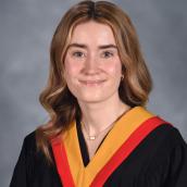 A smiling woman is wearing a graduation gown.