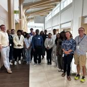 A group of students and staff pose for a photo in the atrium.