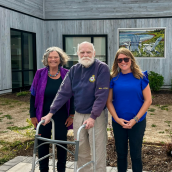 Artist Joy Laking stands with her husband, Jim, and daughter, Danica, in front of her painting Chairs at High Tide during a celebration in the Healing Garden at North Cumberland Health Care Centre.