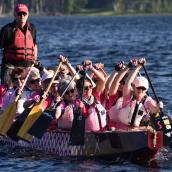 A group of people rowing a boat, highlighting teamwork and outdoor recreation. They are participating in a sport on the water and wearing life jackets for safety. 