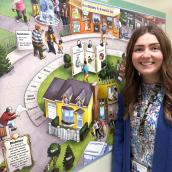 A woman standing next to an educational mural that illustrates diabetes and its effects.