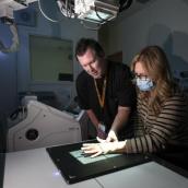 A man stands with arms folded next to an X-ray unit at the hospital.