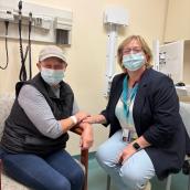 Two women (patient and a doctor) sitting next to each other in a clinic room.