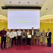 A group of people posed for a photo with two members of the group holding awards. 