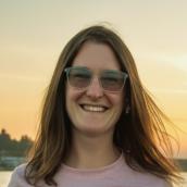 Woman in her thirties with long brown hair and glasses at sunset.