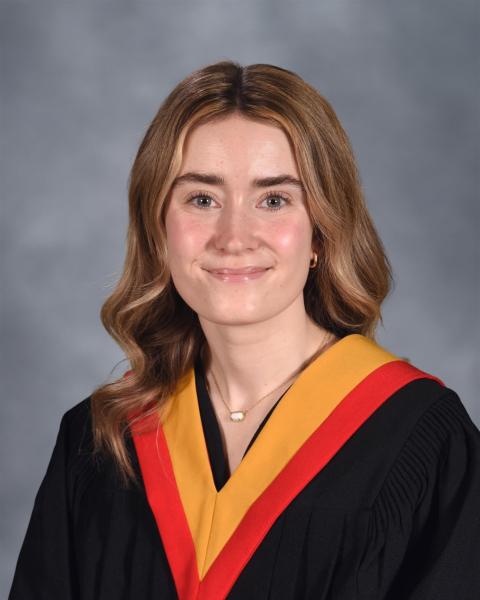 A smiling woman is wearing a graduation gown.
