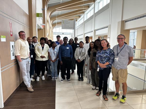 A group of students and staff pose for a photo in the atrium.