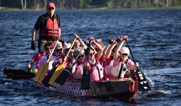 A group of people rowing a boat, highlighting teamwork and outdoor recreation. They are participating in a sport on the water and wearing life jackets for safety. 