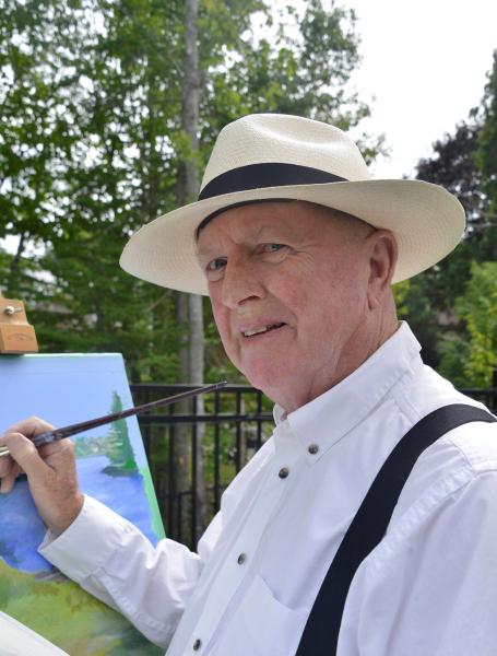 Man wears a white, button-up shirt, suspenders, and a tan and black hat while painting outdoors with trees behind him.