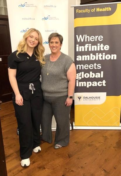 Two women are standing next to each other, both smiling. They are indoors in a setting related to Dalhousie University and Nova Scotia Health.