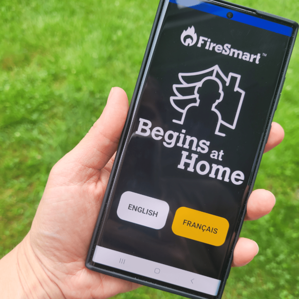 A person holding a phone showing the Firesmart Canada App