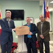 Three men stand together wearing business suits and smiling at the camera.