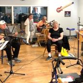 A group of people indoors playing musical instruments. 
