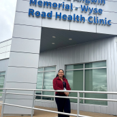 Picture of a woman standing outside a building Dr. Maria Angwin Memorial - Wyse Road Health Clinic.