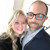    A smiling couple poses closely together for a selfie in a bright indoor setting. 