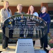 Photo of St. Martha's Legacy monument with 4 people standing behind it