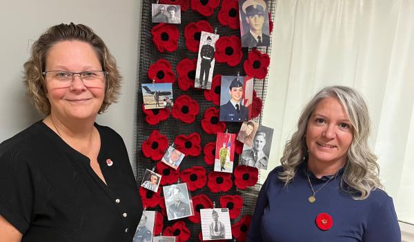 Two smiling women are standing in front of an indoor display filled with vibrant colours and images. 