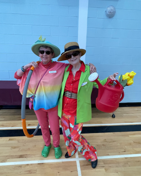 Two women wearing stylish hats are standing indoors.