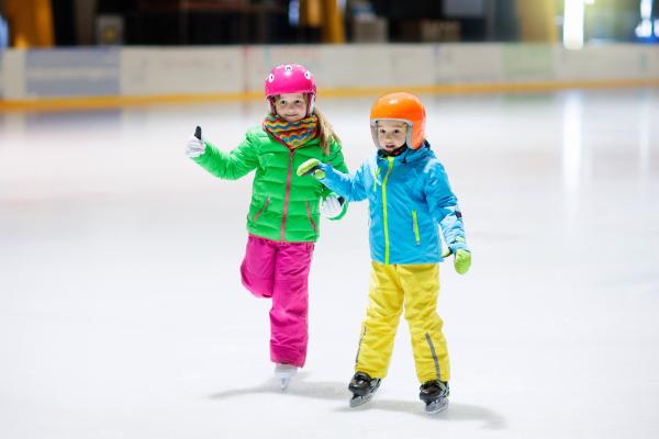 Children ice skating wearing helmets