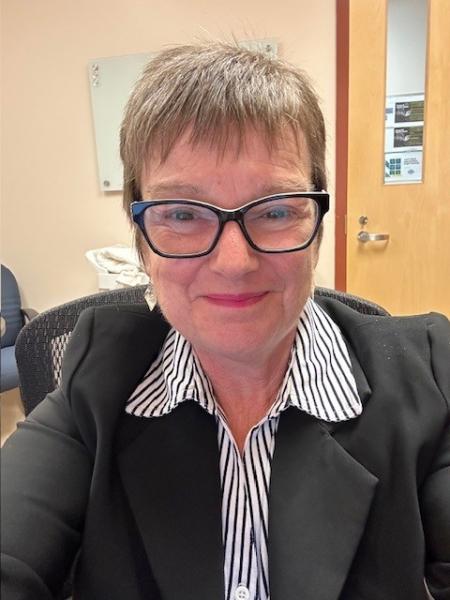 A photo of Valerie Nugent, on her own, smiling at the camera. 