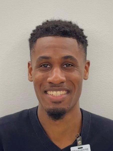 Headshot of a man wearing a black shirt and name badge is smiling at the camera.