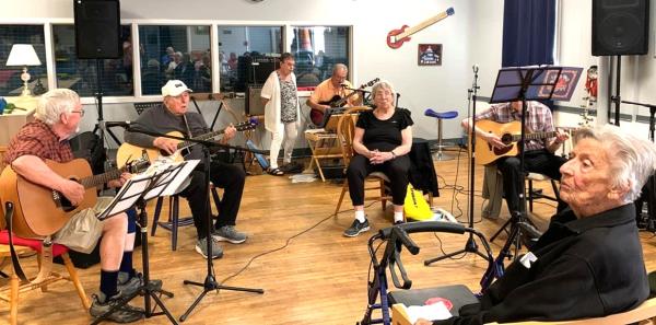 A group of people indoors playing musical instruments. 