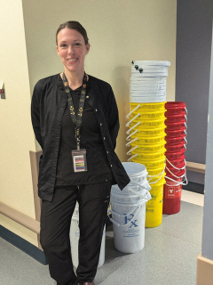 A woman with all black clothing. She has a black landyard with her badge on the end of it. Her hair is brown and tied back