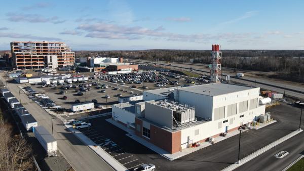 A drone shot of a hospital, parking lot, and a facility under construction in the background.