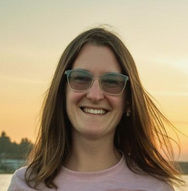 Woman in her thirties with long brown hair and glasses at sunset.
