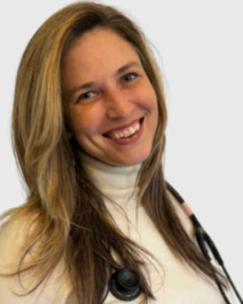 Picture of a woman with long light hair smiling wearing a white turtleneck and a stethoscope around her neck.