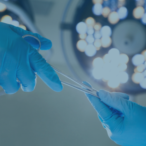 A gloved hand passing a set of forceps to another gloved hand.