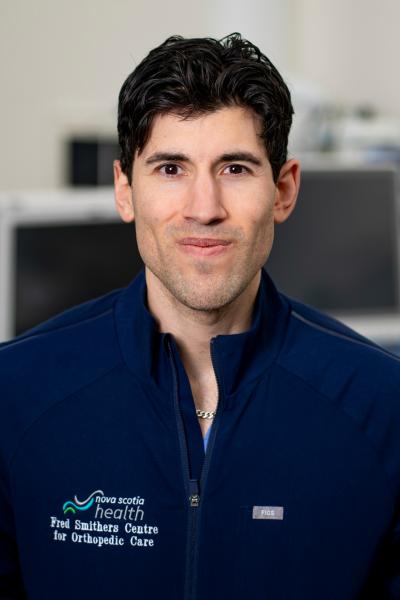 Dr. Jhase Sniderman looking directly at camera. He has dark hair and is wearing a Nova Scotia Health shirt.