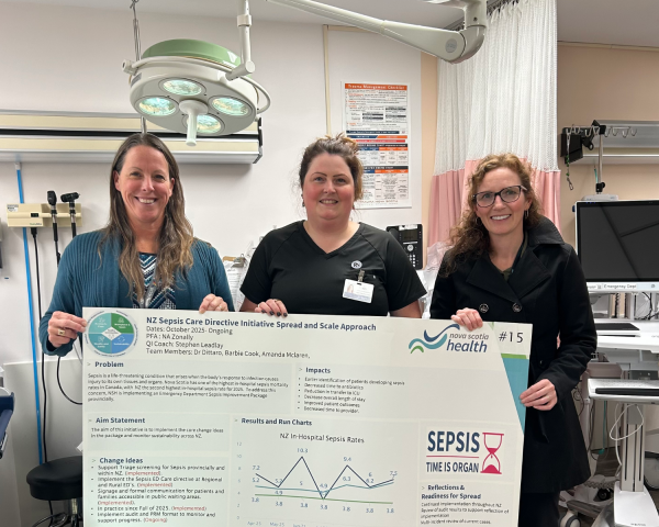 Three health care staff stand in an emergency department, smiling and holding a large poster about the Northern Zone Sepsis Care Directive initiative. Medical equipment, an overhead exam light and a trauma management checklist are visible in the background.