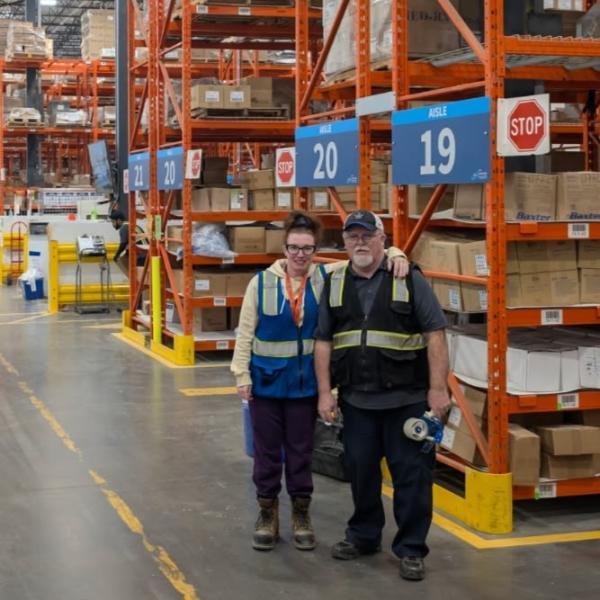 Father and Daughter in coveralls in a warehouse.
