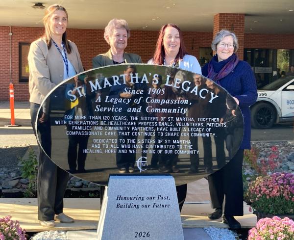 Photo of St. Martha's Legacy monument with 4 people standing behind it