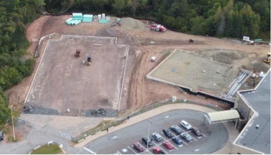 A large area of construction, there are vehicles in the parking lot.  
