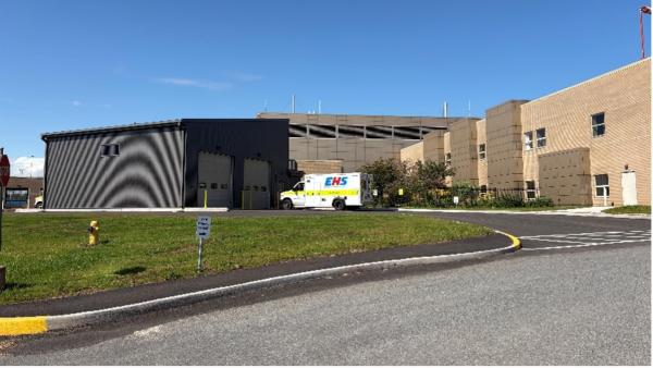 Image of the outside of a healthcare facility with an ambulance driving up to the facility.